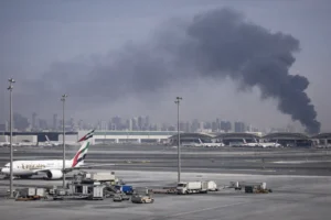 Thick smoke rising near Dubai International Airport as aircraft remain parked on the runway following a security incident