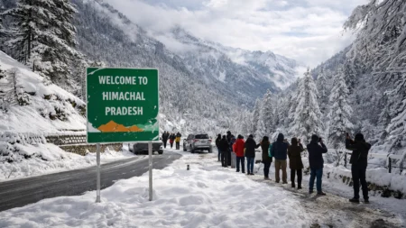 Tourists standing near snow-covered road and mountains after fresh snowfall in Himachal Pradesh
