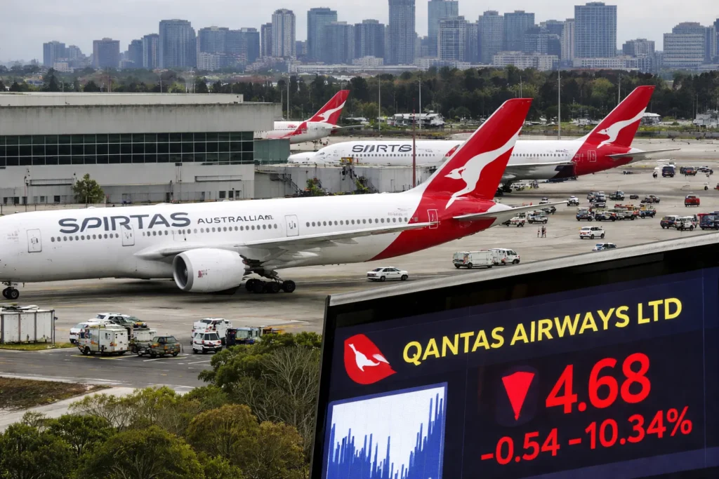 Qantas Shares Drop Over 10% Amid Iran Tensions Qantas aircraft parked at Sydney Kingsford Smith Airport with city skyline in background