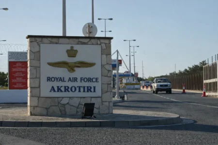 Main entrance sign of RAF Akrotiri military base in Cyprus with security fencing and checkpoint in background
