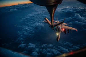 US Air Force KC-135 refueling aircraft performing mid-air refueling operation over clouds during military mission
